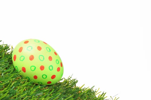 Colorful colored easter egg on artificial grass against white background