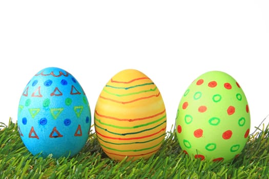 Colorful colored easter eggs on artificial grass against white background