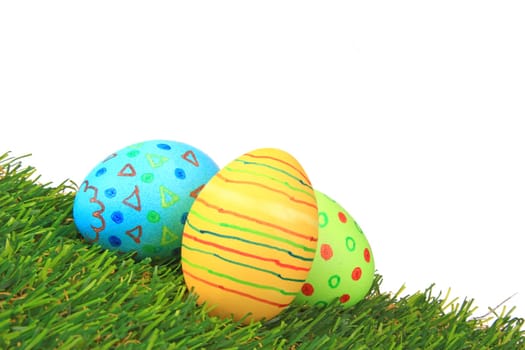 Colorful colored easter eggs on artificial grass against white background