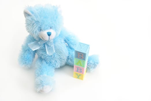 A blue teddy bear sits next to the word baby.