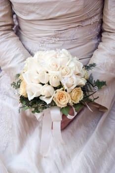 Bride is holding wedding bouquet made from roses
