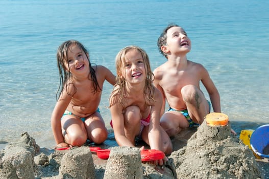 Three kids making castle by the sea