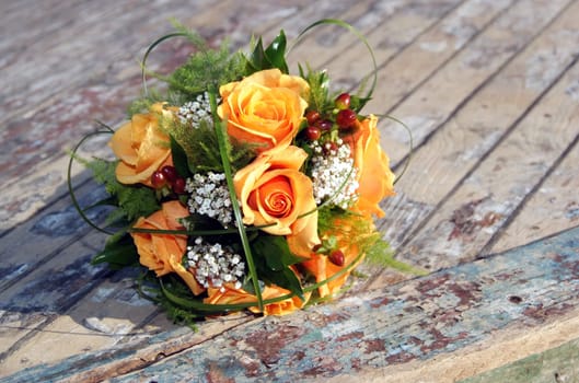 Wedding bouquet made from orange roses on rustic background.