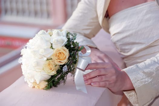 Bride is holding wedding bouquet made from roses