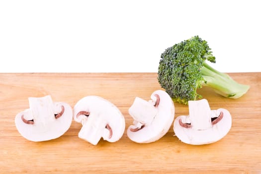 Fresh mushrooms and broccoli on the wooden cutting board