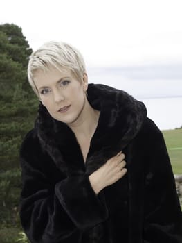 Beautifal blond only wearing a fur coat on balcony
