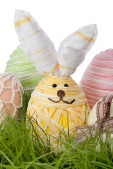 Adorable Easter Bunny Egg handcrafted from straw or raffia entwined around an egg with a smiling face nestled in green grass for the traditional kids Egg Hunt
