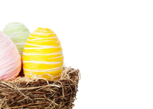 Colourful Easter eggs in a nest isolated over white background, offset from centre to allow space for your text