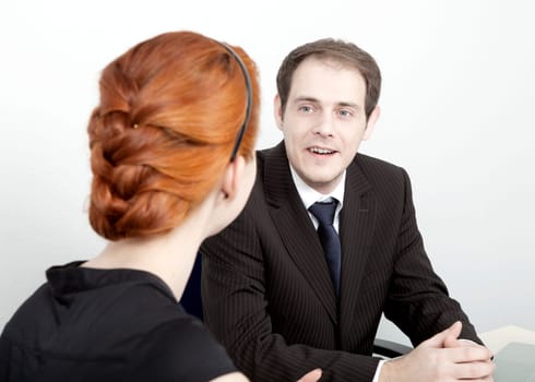 Two business colleagues, a man and woman, having a discussion with the man speaking whlile facing the camera