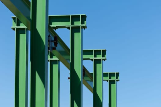 Detail of a small gantry crane painted green against the blue sky