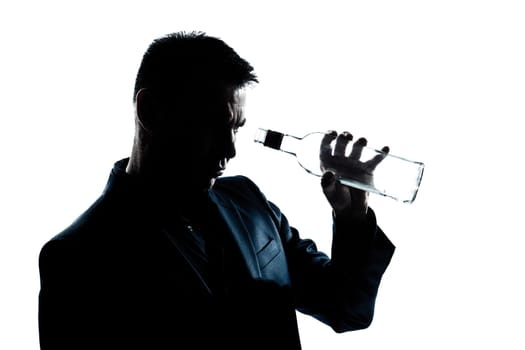 one caucasian man portrait silhouette drunk looking at an empty alcohol botlle in studio isolated white background