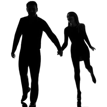 one caucasian couple man and woman running hand in hand in studio silhouette isolated on white background