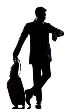 one caucasian  business traveler man checking the time full length silhouette in studio isolated on white background