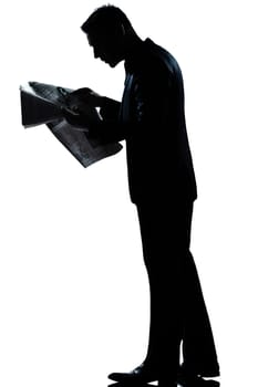 one caucasian man walking reading newspaper  full length silhouette in studio isolated white background