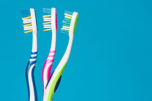 Three tooth brushes on the blue background