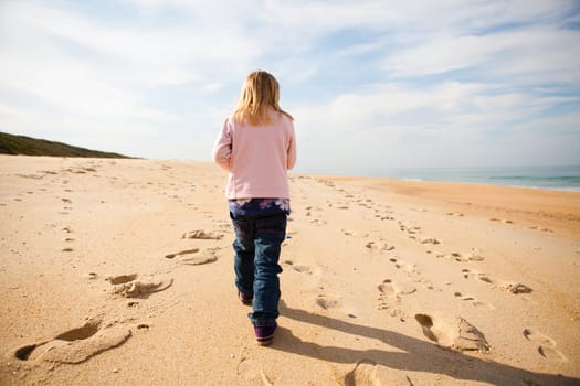 Young girl walking barefoot on beach while on holiday in Portugal