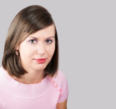 Portrait of a beautiful young woman with a pink top isolated on grey