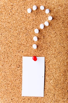 Note paper on cork board with question mark.