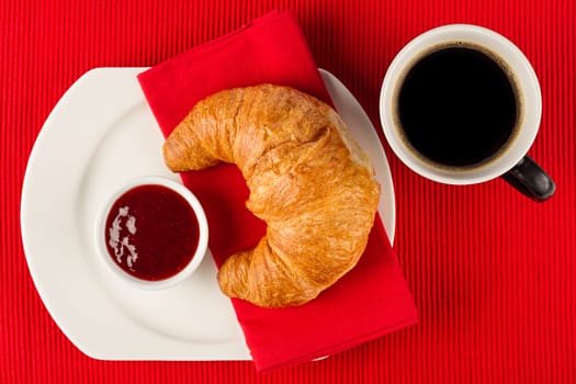 Fresh croissant with jam and coffee