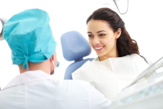 Young woman sitting in a dental chair and looking at doctor
