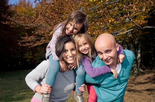 Couple giving two young children piggyback rides smiling