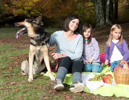 Mother with two doughters and a dog on picnic in forest