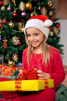 Cute little girl sitting in front of christmas tree