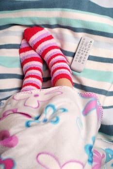 Legs, warm socks and remote control on the blanket