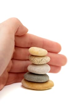 Hand protecting stack of pebbles