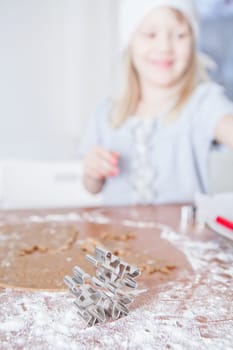 Closeup of star shaped gingerbread dough cutter with happy smiling young girl in background