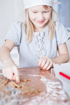 Happy smiling young girl pointing to star shaped piece of dough for making gingerbread biscuits