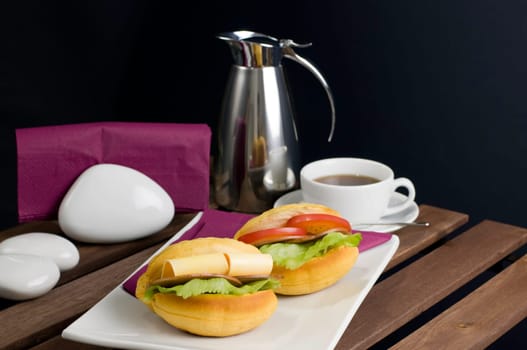 Two sandwich on white china plate, cup of tea and thermos on table