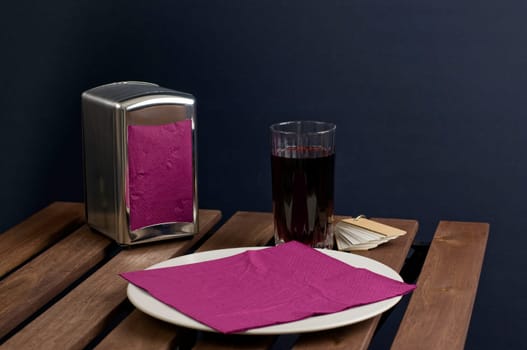 Napkin on china plate and juice in glass on wooden table