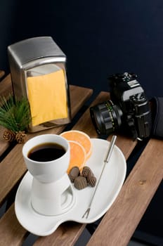 China fondue set, camera and orange slice on wooden table