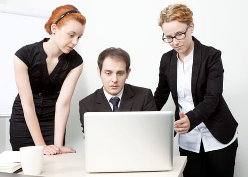 Business people having a meeting as they get together around a laptop computer to share ideas and make an analysis as a united team