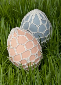 Traditional hand decorated Easter Eggs with an unusual covering of crocheted net nestling in green grass waiting to be found by the children during the Easter Egg Hunt