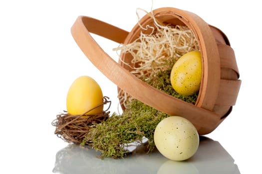 Basket of eggs on its side with moss and straw with one egg still in the basket.