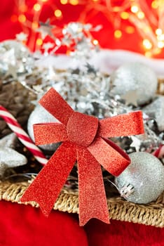 A large red New Year's shiny bow against the background of New Year's toys and beautiful bokeh. New Year and Christmas celebration concept