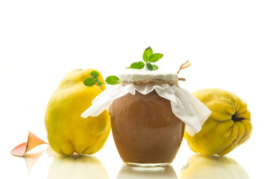 Ripe quince fruit with jam in a glass jar isolated on a white background. Autumn recipes.