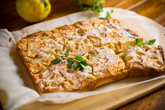 prepared curd semolina pie with quince inside and covered with powdered sugar on a wooden board.