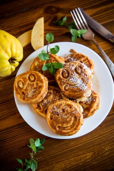 Cooked fried round pancakes with quince filling, cute pancakes with a smile, autumn recipes, on a wooden table