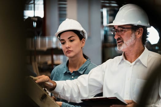 Factory manager inspecting industrial steel machinery and overseeing while supervising and enhancing quality control process for metal material product. Exemplifying