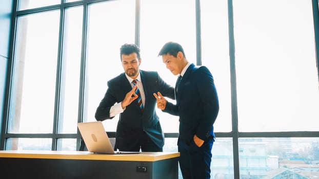 Two business people talk project strategy at office meeting room. Businessman discuss project planning with colleague at modern workplace while having conversation and advice on financial report. Jivy