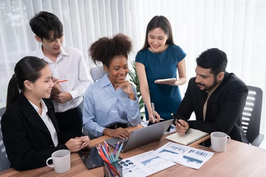 Multiracial analyst team use BI dashboard data to analyze financial report on meeting table. Group of diverse business people utilize data analysis by FIntech for success business marketing. Concord