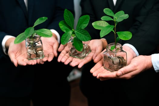 Business people holding money savings jar filled with coins and growing plant for sustainable financial planning for retirement or eco subsidy investment for environment protection. Quaint