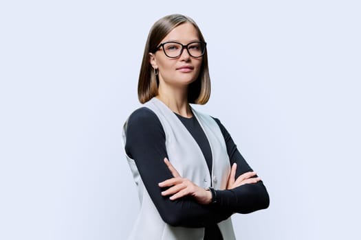 Serious confident young woman with eyeglasses, crossed arms posing on white studio background. Attractive female in black and white clothes. Beauty fashion style youth business job work staff employee