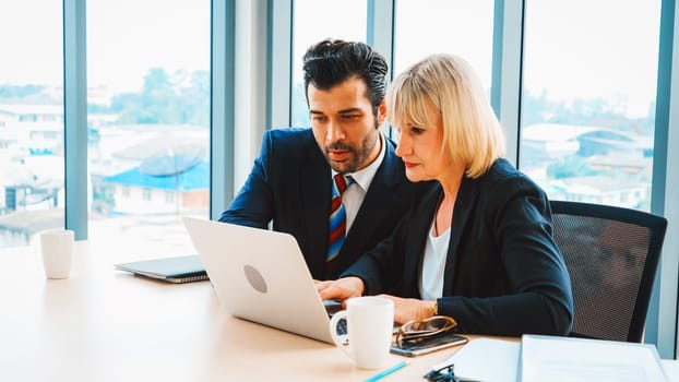 Two business people talk project strategy at office meeting room. Businessman discuss project planning with colleague at modern workplace while having conversation and advice on financial report. Jivy