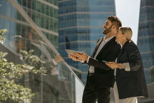 Business colleagues working on project while standing outdoors on skyscrapers background