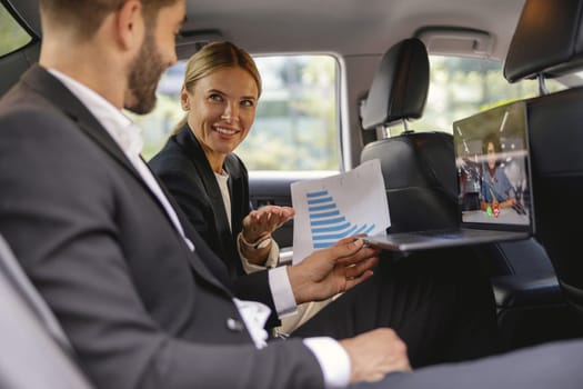 Successful business analysts couple working together during video conference in back seat of car