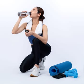 Athletic and sporty asian woman resting and drink water after intensive cardio workout training. Healthy exercising and fit body care lifestyle pursuit in studio shot isolated background. Vigorous